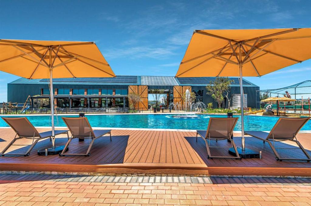 比勒陀利亚Crystal Lagoon Homes的一个带两把椅子和两把遮阳伞的游泳池