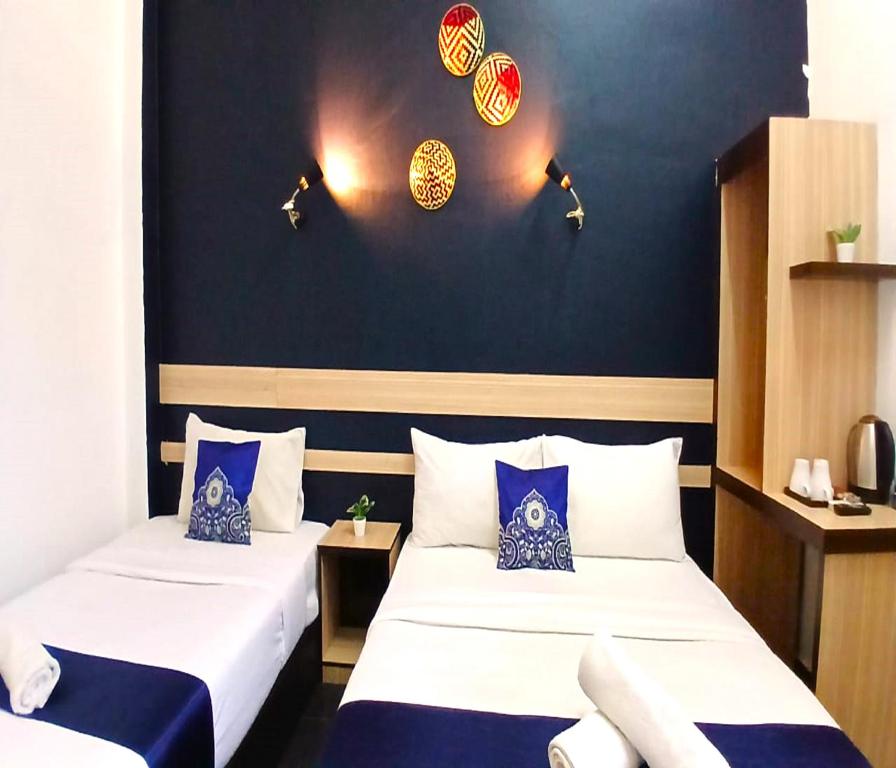 Kota BharuAlia Express Green Mango, Kota Bharu的蓝色墙壁客房的两张床