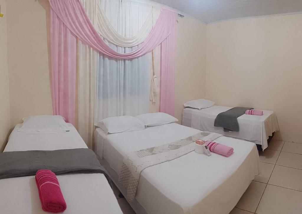 MateirosMACEDO HOSPEDAGEM的客房设有三张床和带粉红色窗帘的窗户。