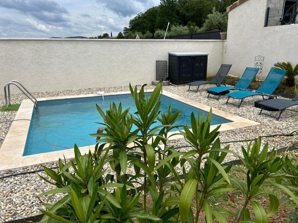 瓦隆蓬达克Vacances en Ardèche "maison pont d'arc"的一座带蓝色椅子的游泳池,位于大楼旁