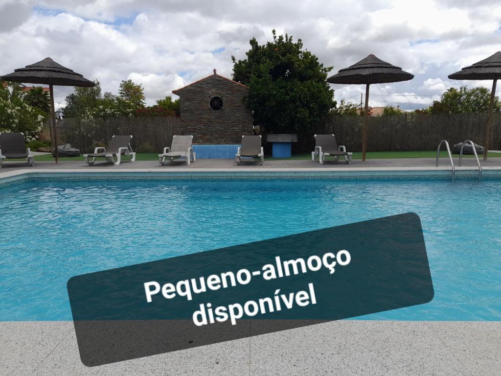 雷根古什-迪蒙萨拉什Terras de Monsaraz的游泳池旁的标志,带椅子和遮阳伞
