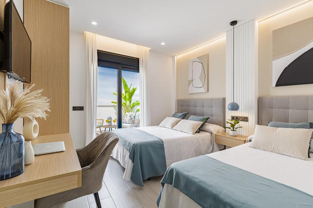 马拉加Stay Belonio的酒店客房配有两张床和一张书桌