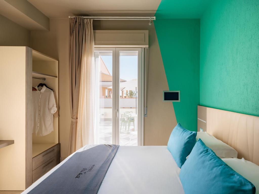 毕博纳的码头尼娜酒店的一间卧室配有一张带绿色床头板的床和窗户