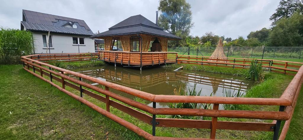 HoryniecZacisze na Roztoczu的池塘周围的木栅栏,带凉亭