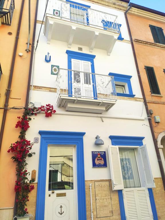 圣贝内代托-德尔特龙托Acasadelpescatore的白色的建筑,设有蓝色的窗户和阳台