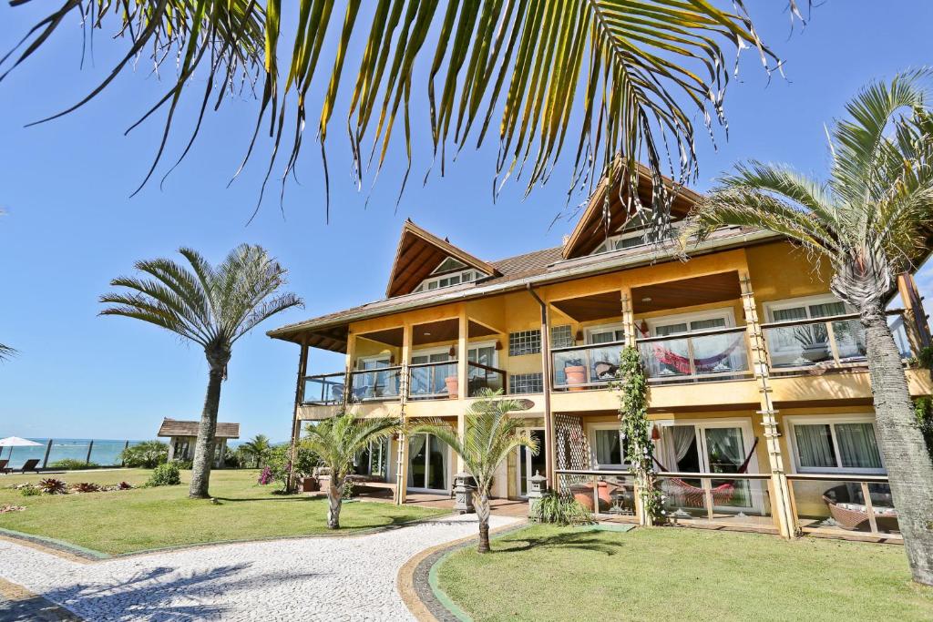 巴拉奈里奥-坎布里乌Estaleiro Guest House的前面有棕榈树的房子