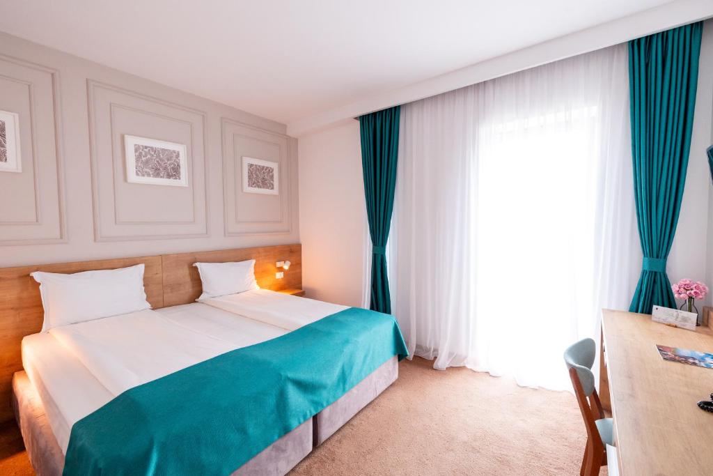 布加勒斯特Stil Hotel的一间卧室配有一张带蓝色窗帘的床和一扇窗户
