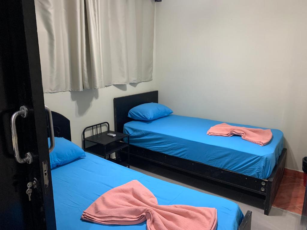 阿莱曼PORTO MARINA North Coast -الساحل الشمالي بورتو مارينا العلمين的小客房内的两张床,配有蓝色的床单
