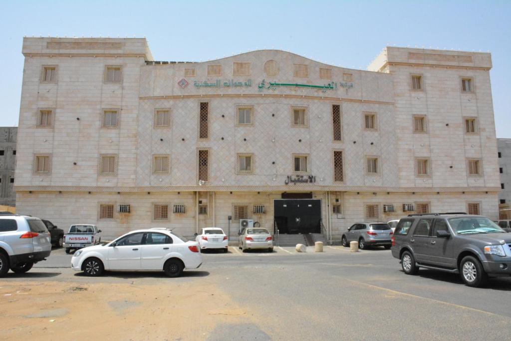 吉赞العيرى للشقق المخدومه جازان 1的一座大型石头建筑,停车场内有车辆停放
