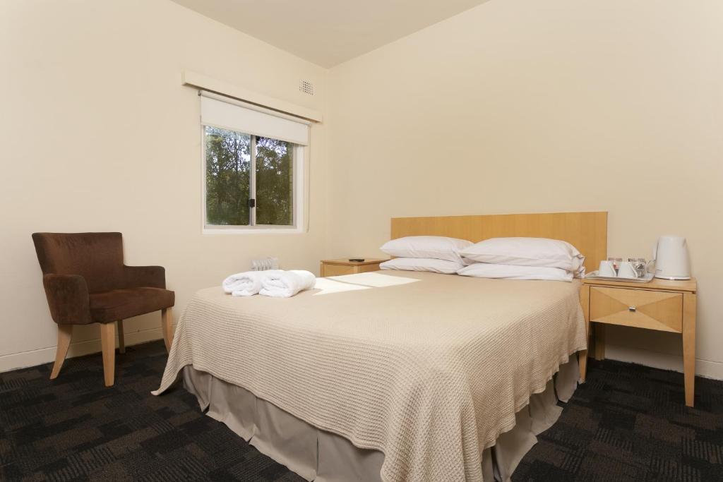 杰斯蒙Shortland Budget Accommodation的一间卧室配有一张带桌子和椅子的床