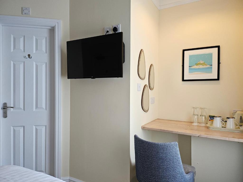 纽基壁虎休憩住宿加早餐旅馆的卧室设有壁挂式电视和蓝椅。