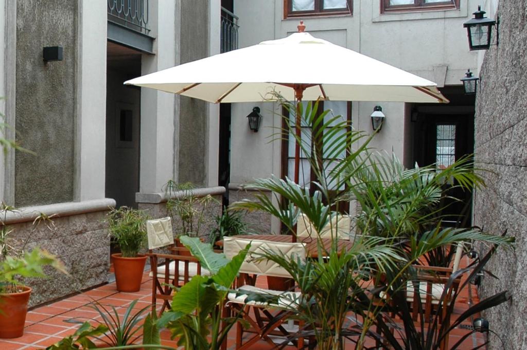 布宜诺斯艾利斯波萨达高登酒店的一个带雨伞、桌子和植物的庭院