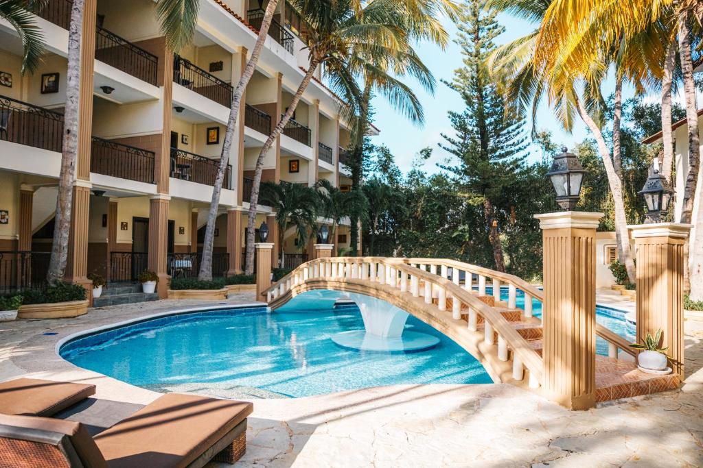 蓬塔卡纳Hotel Brisa的棕榈树酒店游泳池上的桥梁