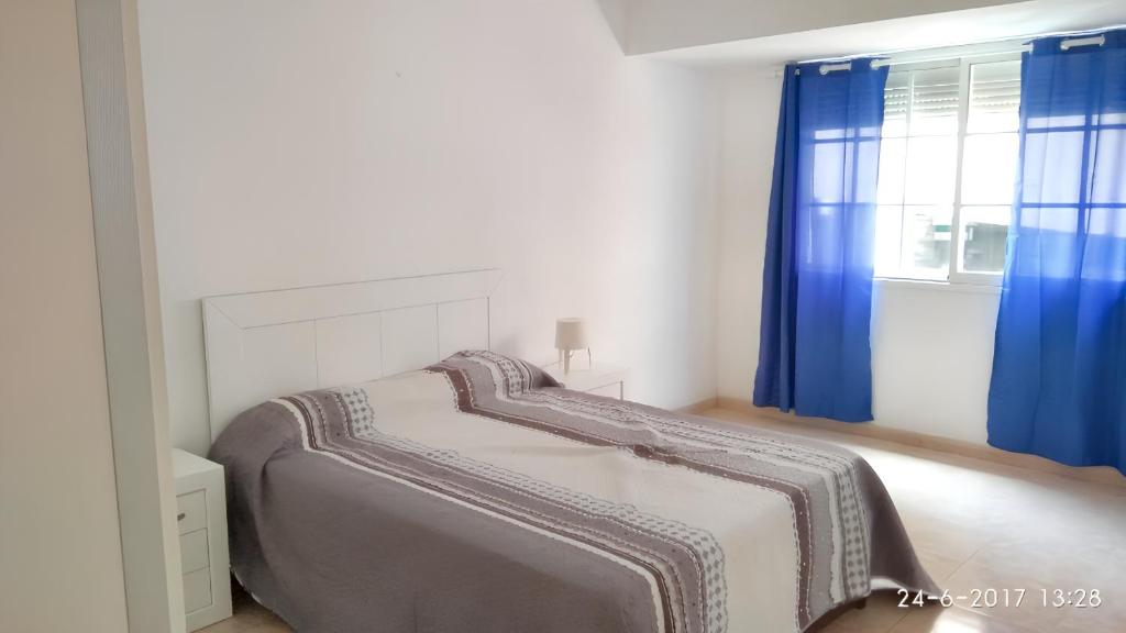 阿雷西费3 bedrooms apartement at Arrecife 800 m away from the beach with balcony and wifi的一间卧室配有床和蓝色窗帘的窗户