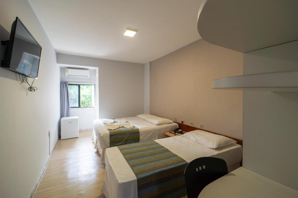 若昂佩索阿Lagoa Park Hotel的小房间设有两张床和电视