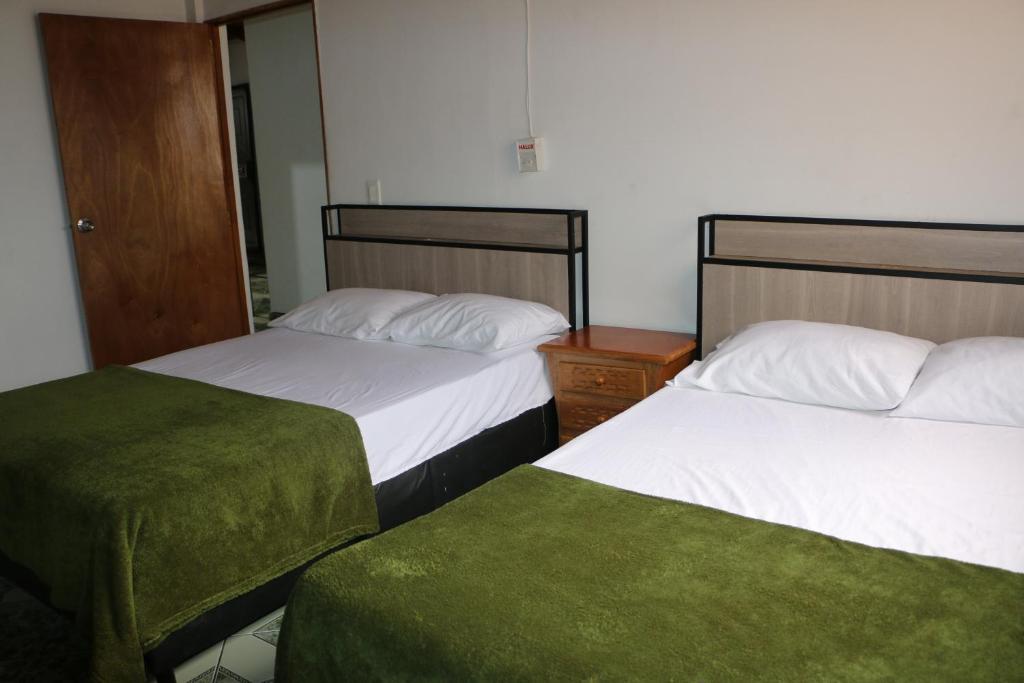 麦德林Aparta Suite Torre De Prado Penthouse的配有绿床单的酒店客房的两张床