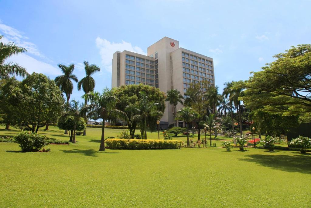 坎帕拉Sheraton Kampala Hotel的一座大建筑,位于公园里,有树木和草地
