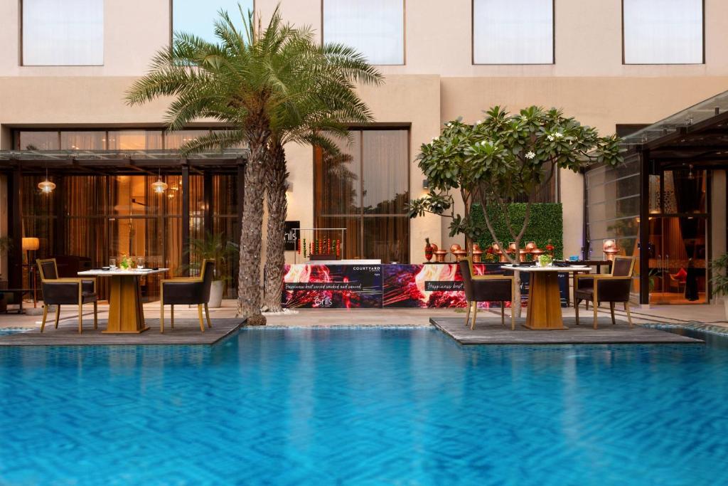 阿格拉阿格拉万怡酒店的一座带桌椅的游泳池位于大楼旁