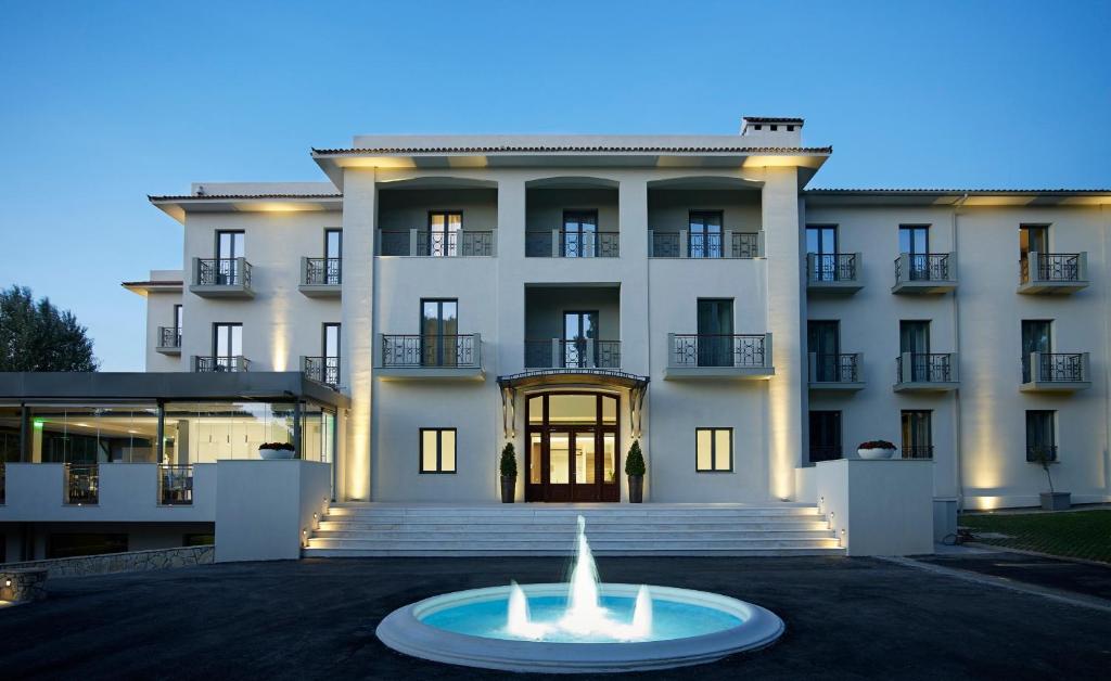 雅典多莫特尔卡斯特里酒店的一座白色的大建筑,前面有一个喷泉