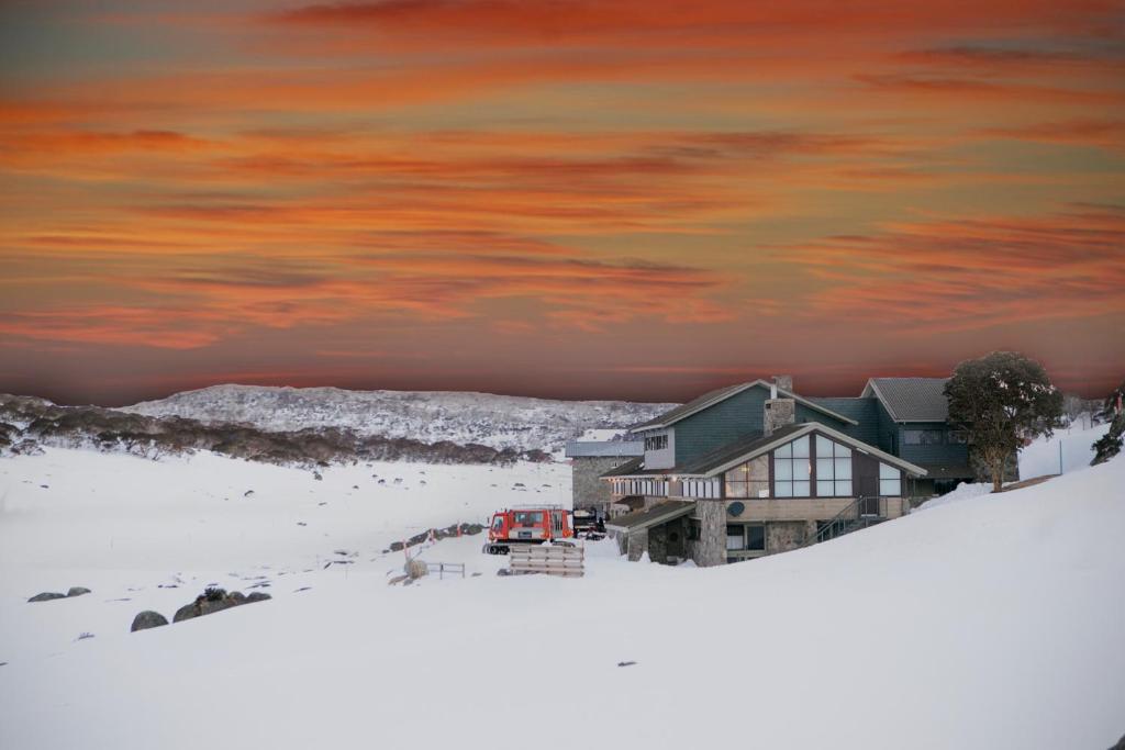 佩里舍峡谷Barrakee Ski Lodge的雪中的房子,里面装着一辆红色的卡车