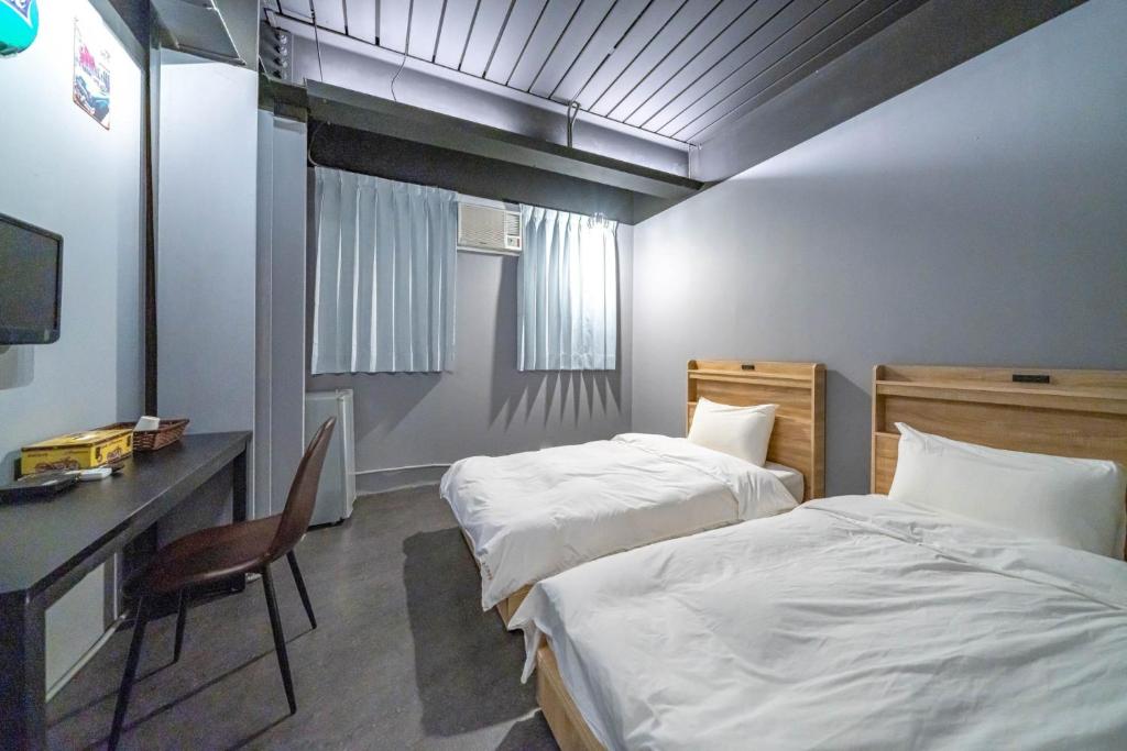 Dalin曼橙驛站的酒店客房设有两张床、一张桌子和一台电脑。