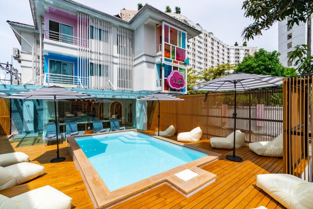 普吉镇The Tint At Phuket Town - SHA Plus的木制甲板上带遮阳伞的游泳池