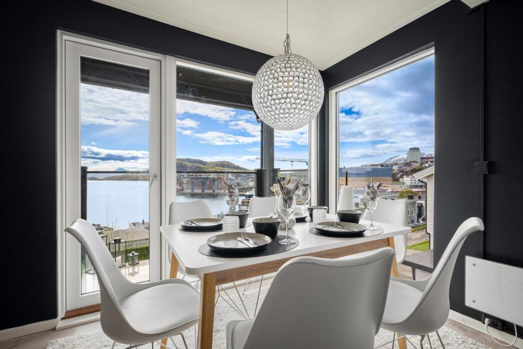 哈尔斯塔AA Home Solgryveien Harstad的一间设有白色桌椅和大窗户的用餐室