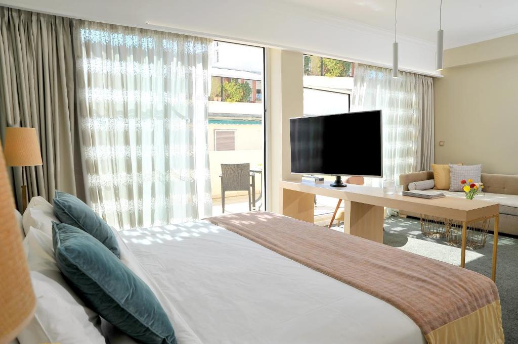 雅典爱若特斯特拉托斯瓦西利科斯酒店的一间卧室配有一张床和一张书桌及电视