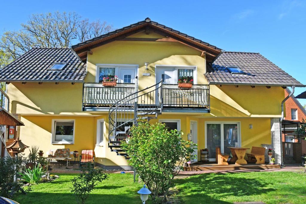 巴贝Ferienwohnungen Familie Dinda的带阳台和庭院的黄色房子