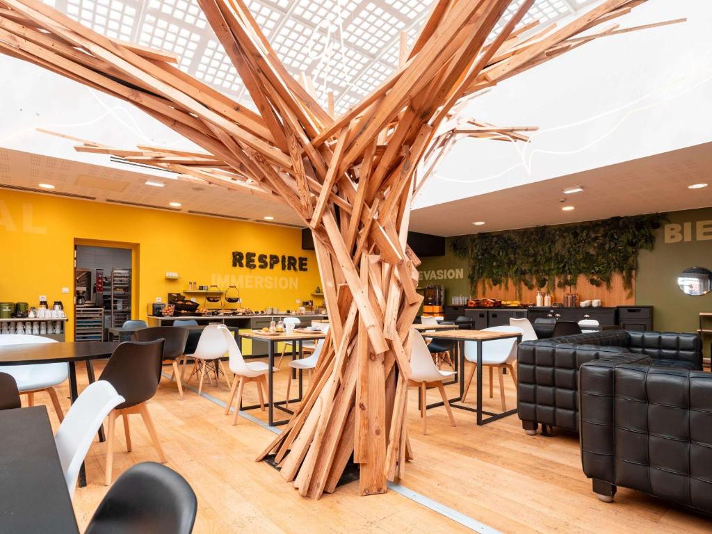 加来加来市中心宜必思尚品酒店的餐厅的一棵大木树,配有桌椅