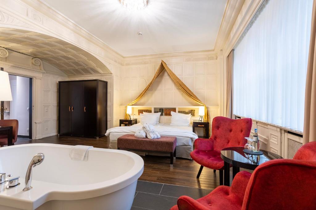 巴登-巴登Batschari Palais Baden-Baden的带浴缸和床的酒店客房