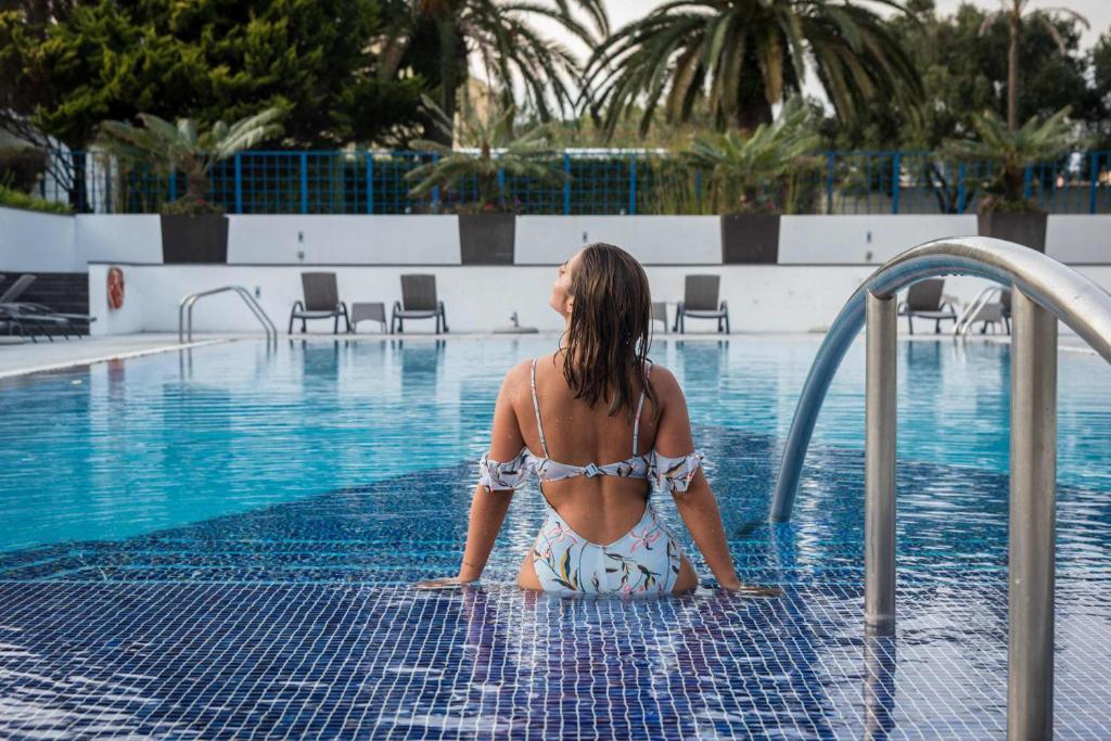 蓬塔德尔加达阿佐里斯皇家花园 - 休闲及会议酒店的坐在游泳池里的比基尼女人