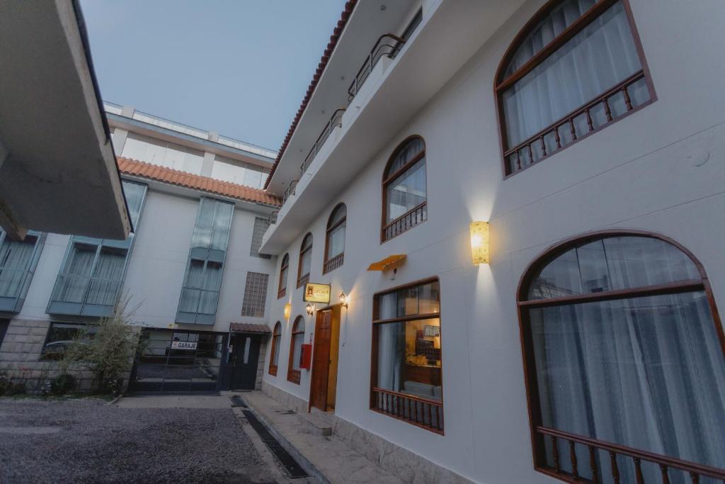 库斯科Quechua ApartHotel的白色的建筑,设有窗户和门