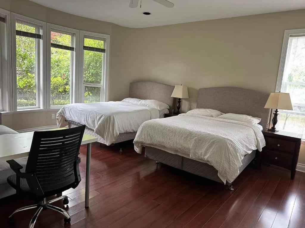 温哥华溫西Ubc如悅民宿的一间卧室配有两张床、一张桌子和两个窗户。