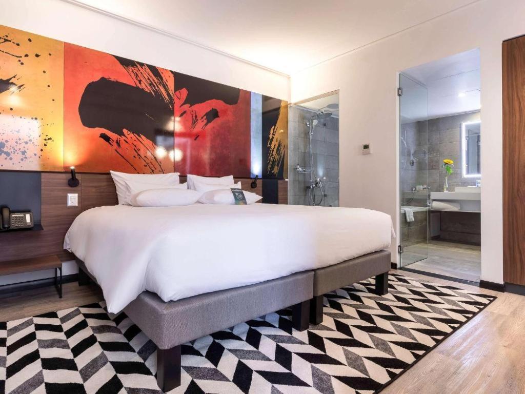 圣地亚哥Novotel Santiago Providencia的一间带白色大床的卧室和一间浴室