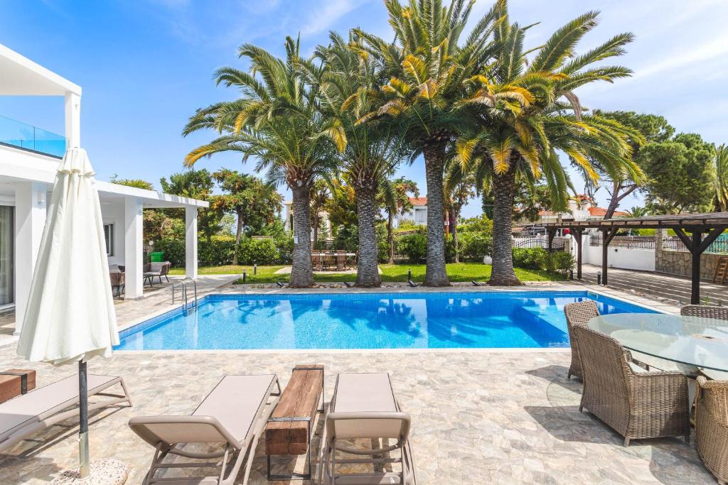 波利克罗诺Albero Villa Polychrono的一个带桌椅和棕榈树的游泳池