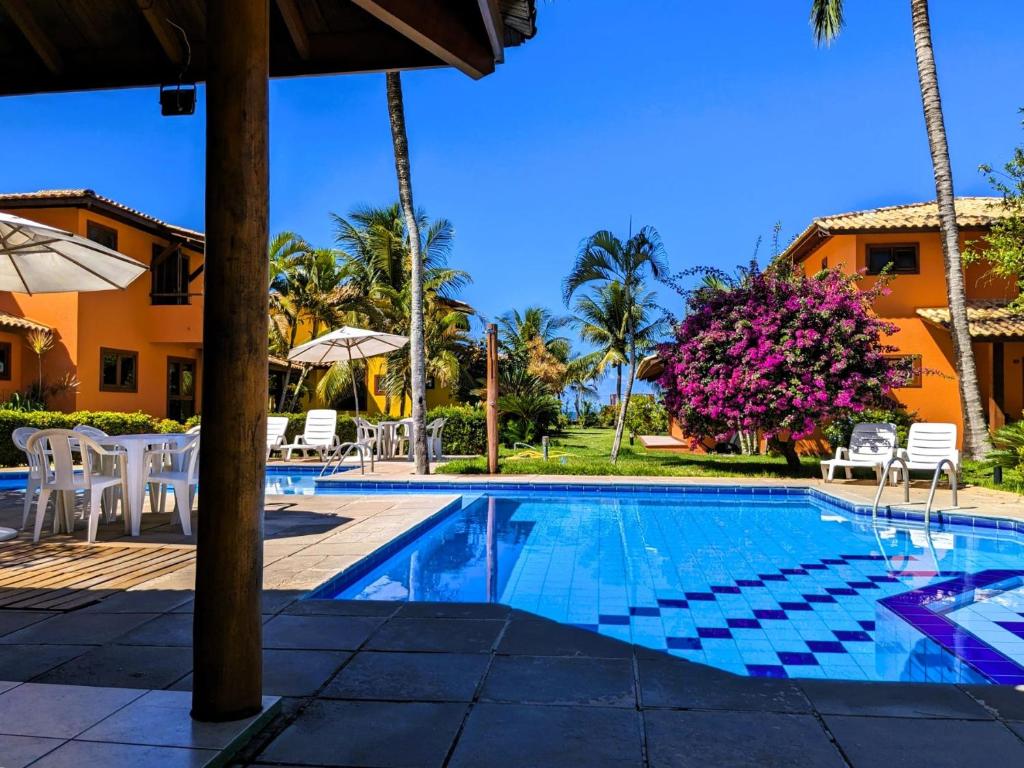 阿拉亚尔达茹达Residence Maria Vittoria Praia Arraial的一个带椅子和树木的度假村游泳池