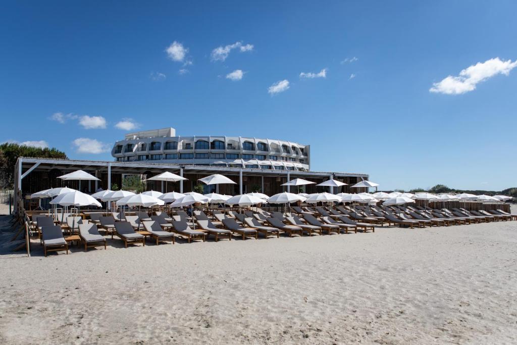 拉格朗德默特Hôtel La Plage 5 étoiles La Grande Motte的海滩上的一组椅子和遮阳伞