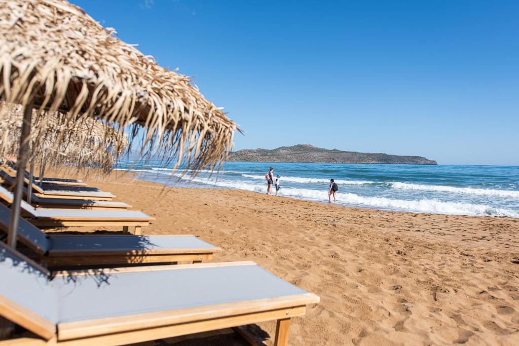斯塔罗斯The Mini Beach Hotel的海滩上一排带草伞的沙滩椅