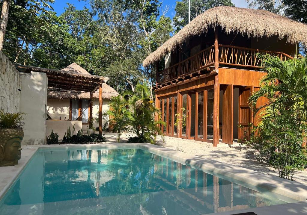 图卢姆Lodge Tzunum Jade的一座带游泳池和茅草屋顶的房子
