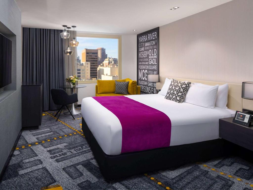 墨尔本Pullman Melbourne City Centre的酒店客房设有一张大床和一张书桌。