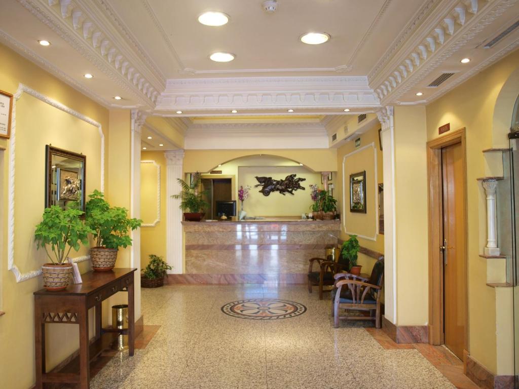 马德里唐路易酒店的大堂设有黄色的墙壁和植物走廊