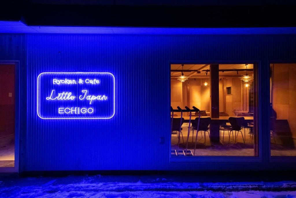 汤泽町Little Japan Echigo的餐厅的一边有蓝色的标牌,有桌子