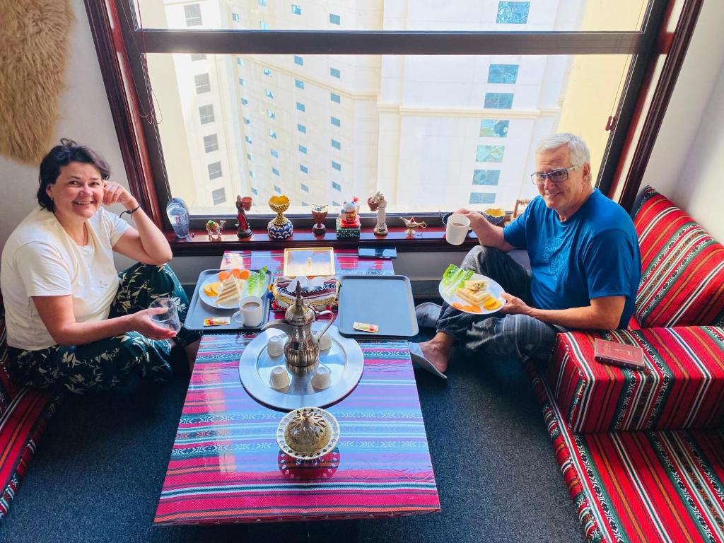 迪拜Dreams beach hostel的坐在餐桌旁吃食物的男人和女人