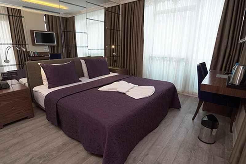 萨姆松ATAKUM PALAS OTEL的一间卧室配有一张紫色床和毛巾