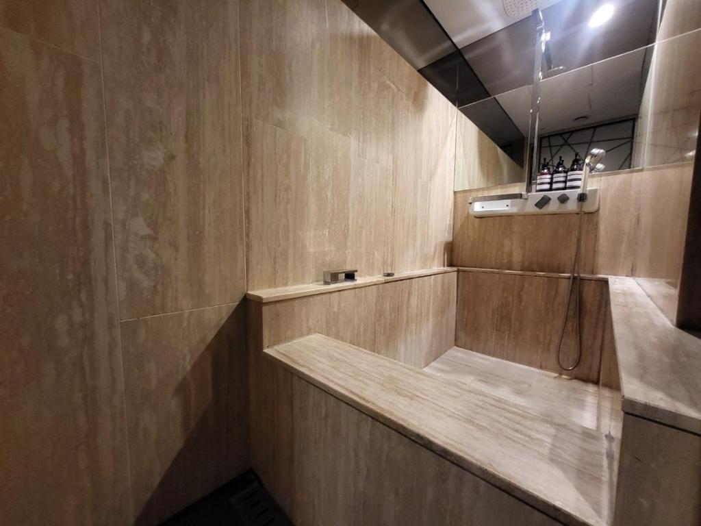 首尔Hotel Cullinan Wangsimni的带淋浴的浴室和木墙