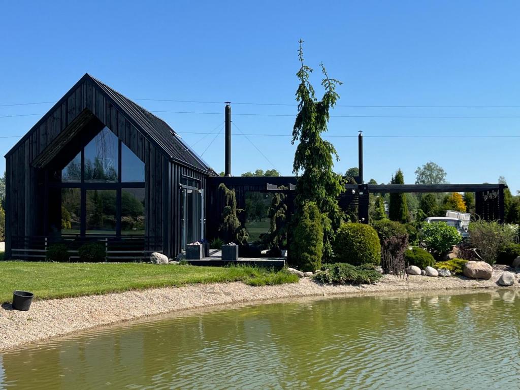 TīnūžiBlack House- Lake garden sauna的水边的黑色房子