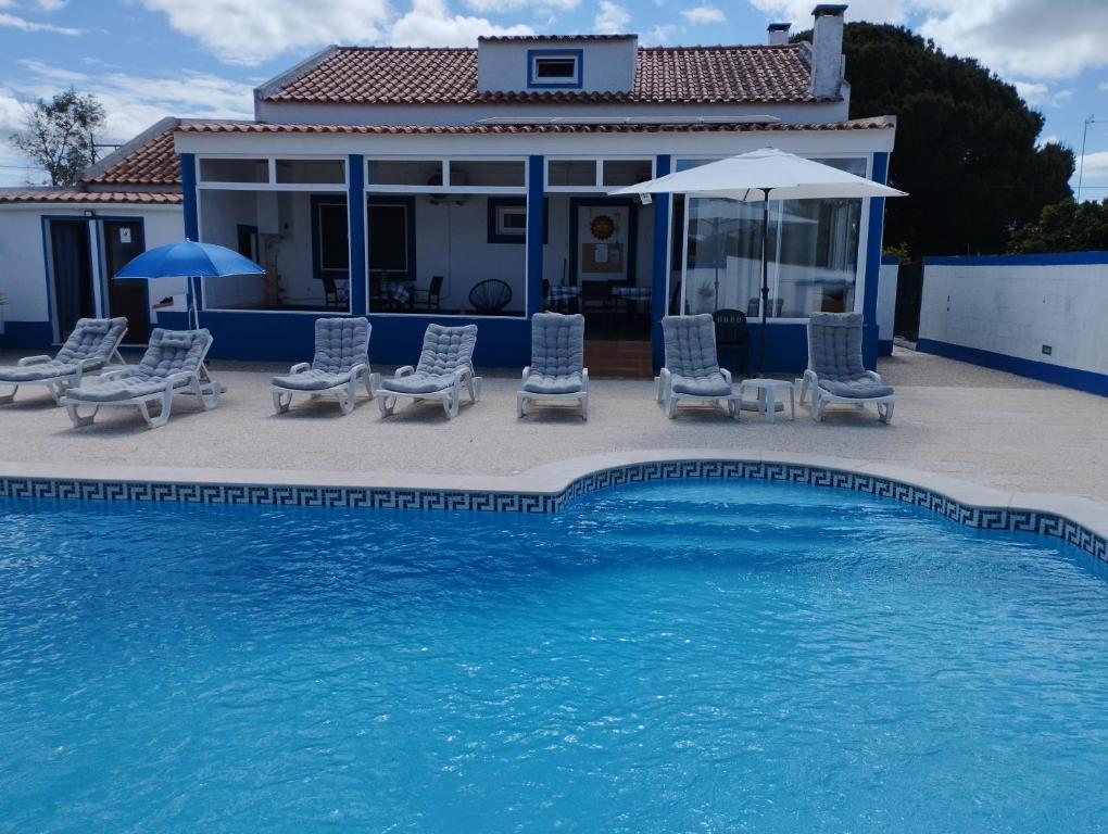 格兰杜拉Monte Sol Nascente (Loft)的房屋旁的游泳池配有椅子和遮阳伞