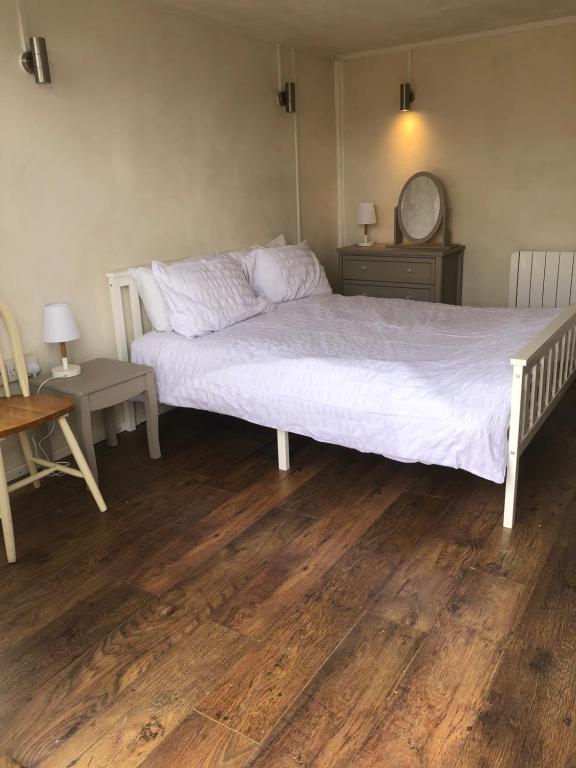 布里德波特Bridport Garden Suite的卧室配有白色的床,铺有木地板