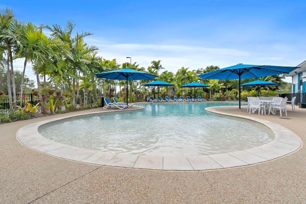 洛坎普顿Quality Resort Parkhurst的一个带蓝伞、椅子和桌子的游泳池